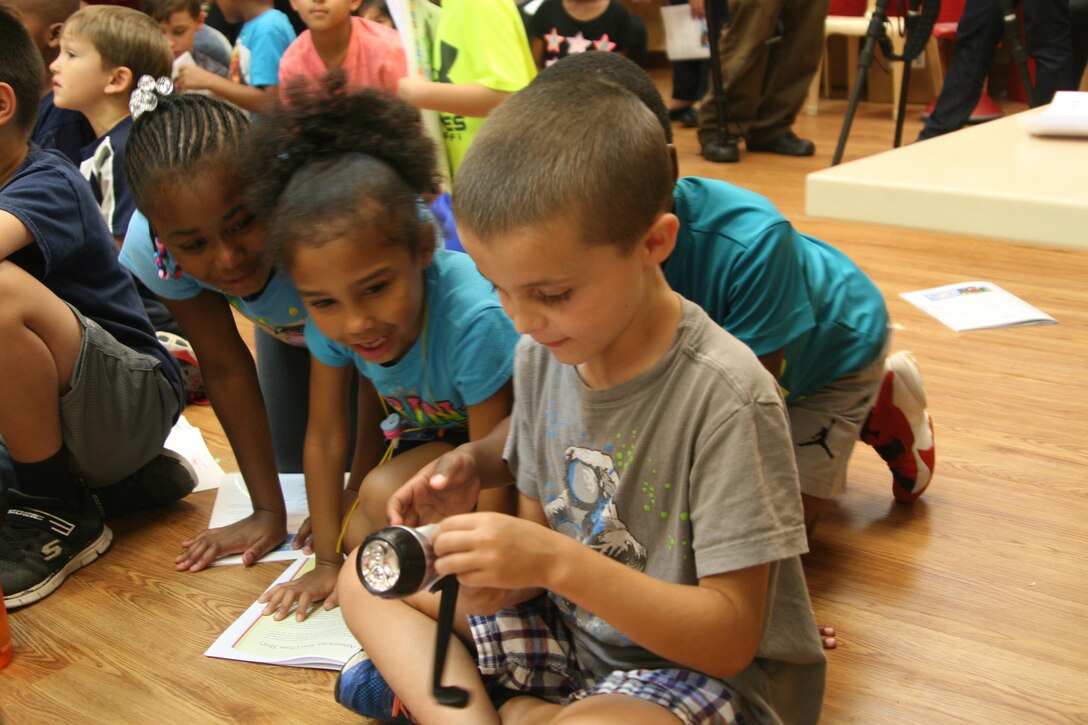 Children at the Quantico Youth Center examine a hand-cranked radio and flashlight, an example of the kind of tool they could keep in their personal pillowcase emergecy preparedness kits. The American Red Cross visited the facility August 8 to present the education session.