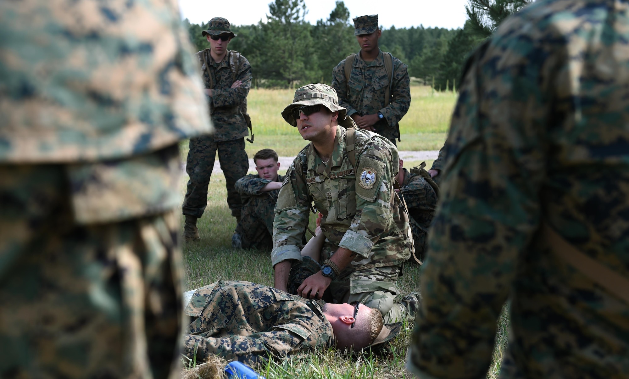Senior Airman Ronnie Perez, 460th Medical Operations Squadron medical technician, instructs U.S. Marines, assigned to Company A, Marine Cryptologic Support Battalion, how to properly apply a tourniquet Aug 17, 2016, at the U.S. Air Force Academy, Colo. Perez volunteered to join the battalion for their summer field training to teach basic life-saving skills service members must know prior to being deployed. (U.S. Air Force photo by Airman Holden S. Faul/ Released)