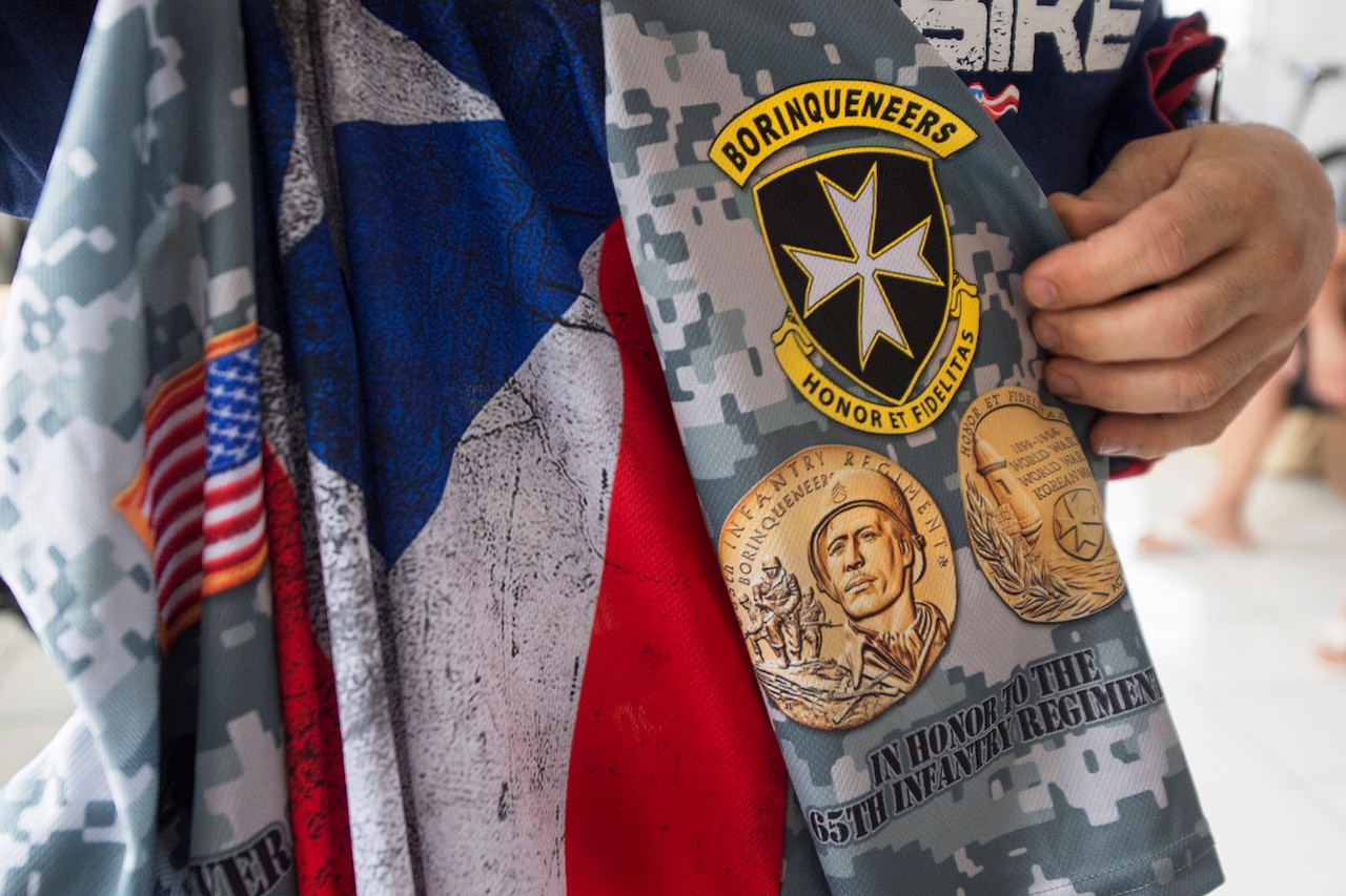 A veteran holds a bicycle jersey with an imprinted emblem of Puerto Rico's 65th Infantry Regiment in Cabo Rojo, Puerto Rico, Aug. 13, 2016. Veterans riding with the Warriors 4 Life nonprofit veterans group dedicated their ride in a 100-kilometer mountain bike race to the regiment famous for its bayonet charge in the Korean War. DoD photo by EJ Hersom
