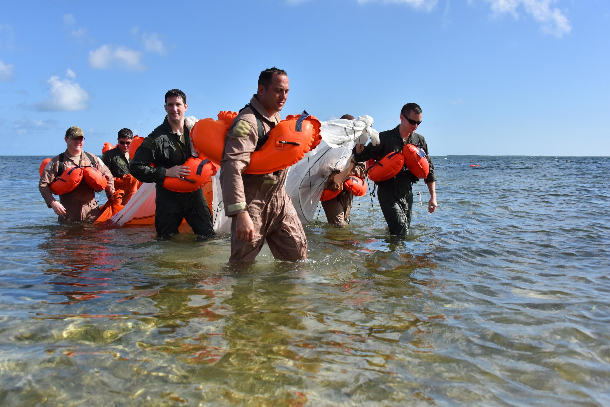 Airmen of the 911th Operations Group bring a parachute to shore after practicing disentanglement at Naval Air Station Key West, Florida, August 18, 2016. To complete this training, Airmen simulated being trapped under the parachute and swam beneath it to the other side. (U.S. Air Force photo by Staff Sgt. Marjorie A. Bowlden)