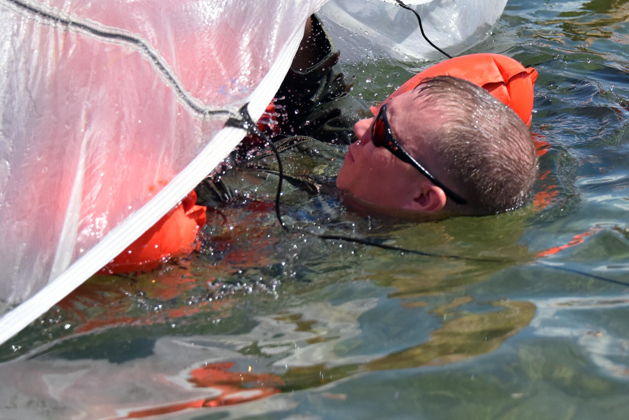 Master Sgt. Michael Thomas, load master with the 911th Operations Group, emerges from beneath a parachute during disentanglement training at Naval Air Station Key West, Florida, August 18, 2016. Airmen swam beneath the parachute to familiarize themselves with the situation and to practice removing themselves in case of an emergency. (U.S. Air Force photo by Staff Sgt. Marjorie A. Bowlden)