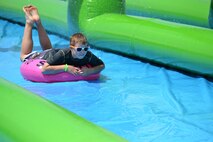 Logan Wilson tubes down a giant slip-and-slide during Slide the City at Schriever Air Force Base, Colorado, Friday, Aug. 19, 2016. Wilson was one of the hundreds of Schriever School Age Care and Ellicott School District students who participated in the event. (U.S. Air Force photo/Brian Hagberg)