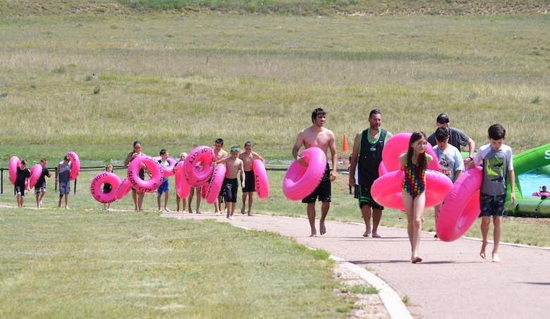 Sliders carry their tubes back up the hill following their trip down a giant slip-and-slide during Slide the City at Schriever Air Force Base, Colorado, Friday, Aug. 19, 2016. This year, the event was moved from the road next to the fitness center to a hill behind the facility to give participants a longer, steeper slide. (U.S. Air Force photo/Brian Hagberg)