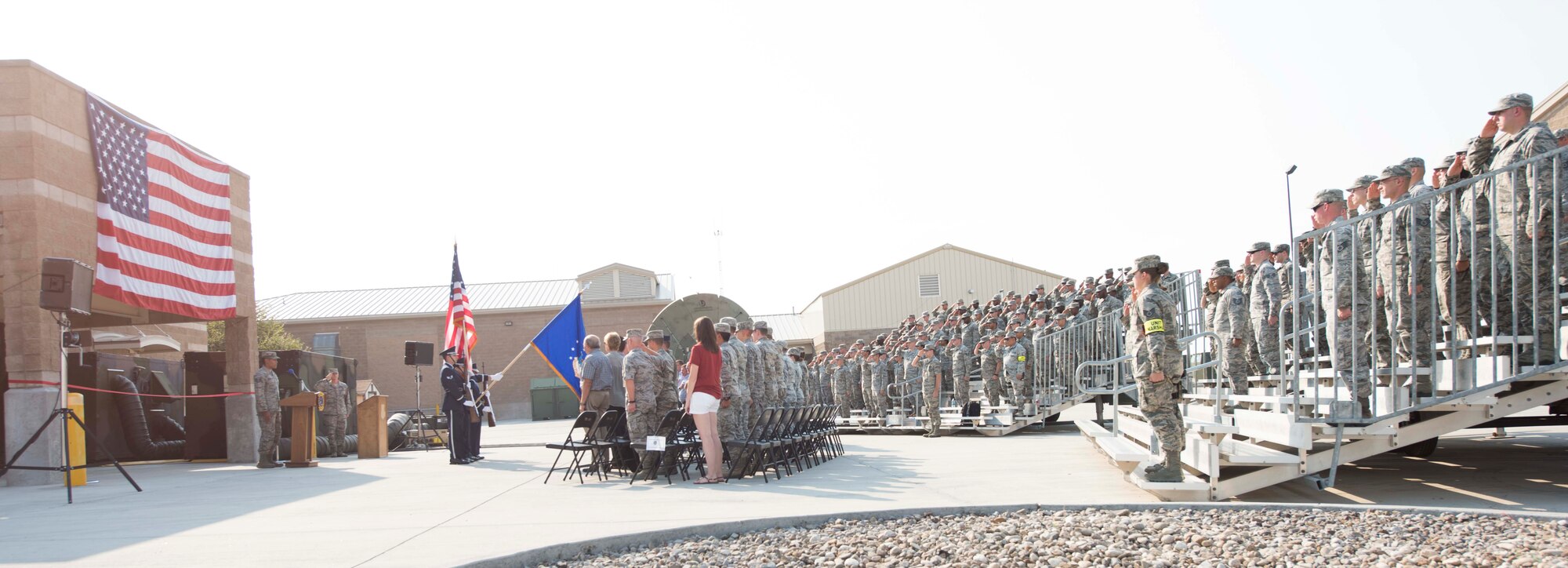 Participants of the 726th Air Control Squadron ribbon cutting ceremony honor the flag as Staff Sgt. Khaiel-Matthew Kuhn-Natividad, 726th ACS interface control technician, sings the national anthem August 18, 2016, at Mountain Home Air Force Base, Idaho. The ceremony was to celebrate the recent renovations to the 726th ACS compound. (U.S. Air Force photo by Airman Alaysia Berry/Released)
