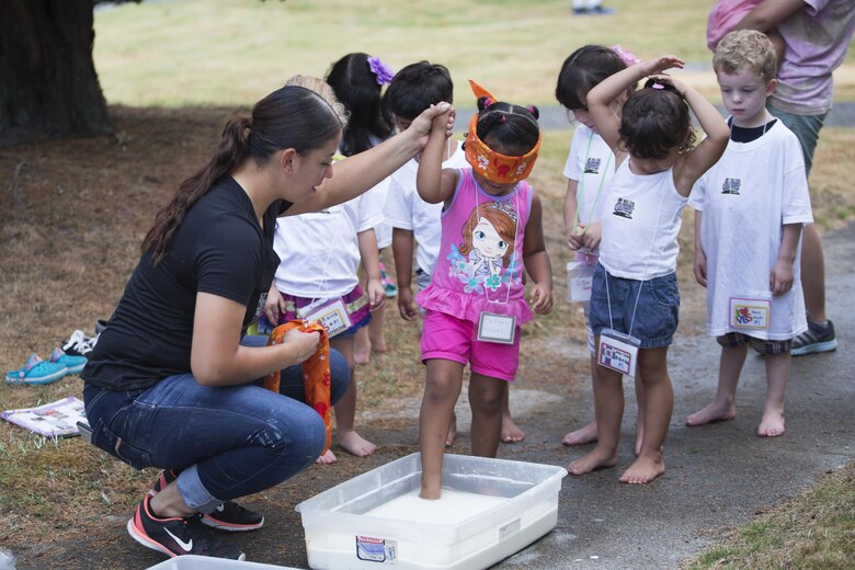 A volunteer helps preschoolers walk through a liquid during Vacation Bible School at the Marine Memorial Chapel on Marine Corp Air Station Iwakuni, Japan, Aug. 16, 2016. Walking blindly through an unknown substance taught the children how to be courageous in an uncomfortable situation. (U.S. Marine Corps photo by Lance Cpl. Joseph Abrego)