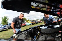 Chief Master Sgt. Jeff Barney, 5th Logistics Readiness Squadron chief enlisted manager, and Tanner Barney look at a 1959 Plymouth Savoy engine at the Rough Rider Golf Course at Minot Air Force Base, N.D.,  Aug. 19, 2016. The Plymouth was part of the annual end of summer block party and car show. (U.S. Air Force photo by Staff Sgt. Chad Trujillo)