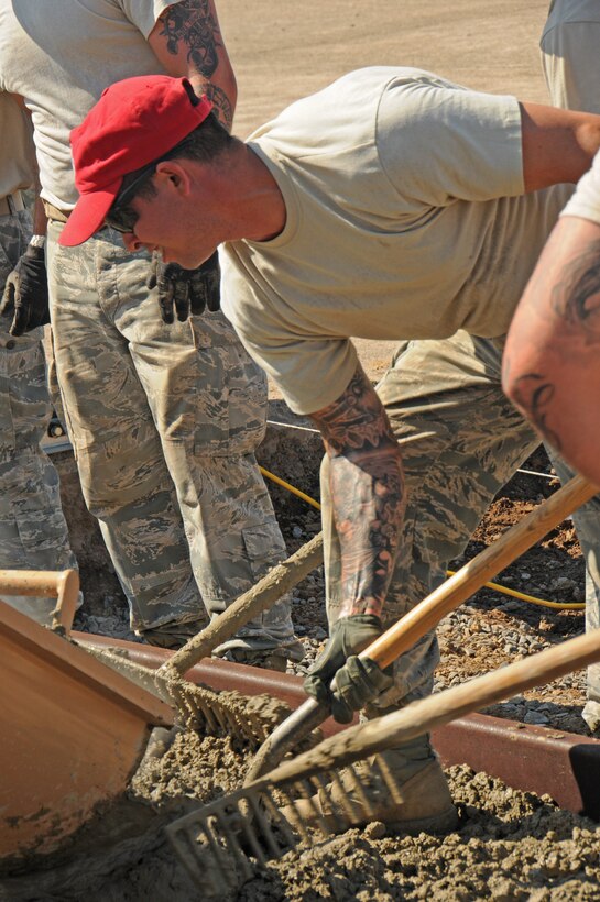 Senior Airman Tyler Dewey, from the 201st Rapid Engineer Deployable Heavy Operational Repair Squadron Engineer Squadron, Det.1, rakes concrete into place with other Airman while laying a concrete slab at Horsham Air Guard Station, Pa., Aug. 14, 2016. As concrete pours from the volumetric concrete mixer, several “Dirt Boys” work to move it around evenly. (U.S. Air National Guard photo Senior by Airman Timi Jones)