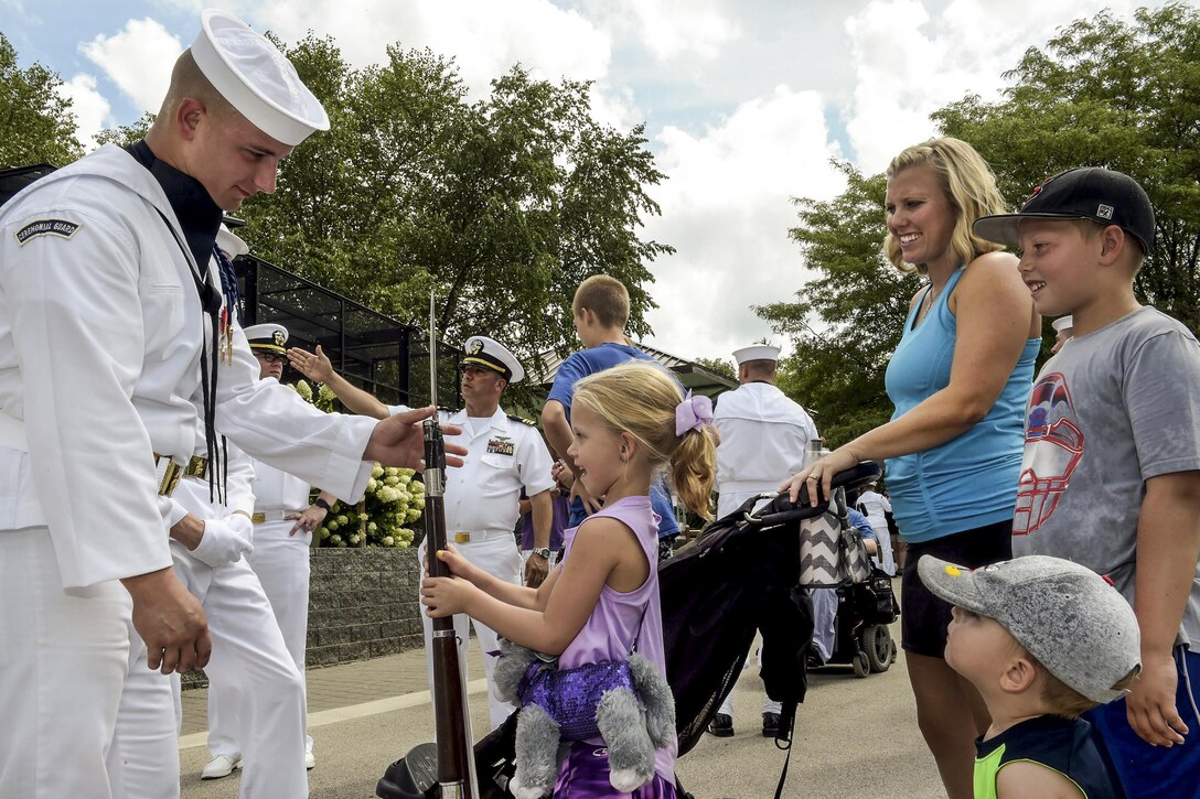 Navy Seaman Brady Smith lets a girl touch a rifle used for performances during Navy Week in Des Moines, Iowa, Aug. 19, 2016. Smith, a member of the Navy's ceremonial guard, is an aviation machinist's mate airman. Navy week helps raise awareness of the Navy through local outreach, community service and exhibitions. Navy photo by Petty Officer 1st Class Gilbert Bolibol