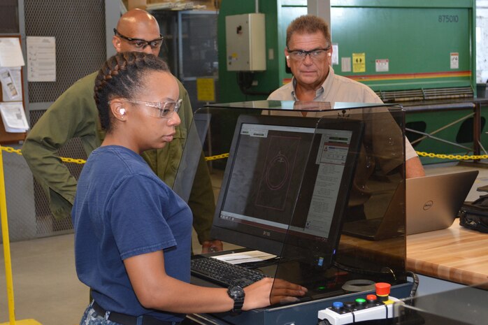 Hull Maintenance Technician Fireman Mionna Green controls the new waterjet fabrication system at Southeast Regional Maintenance Center as Mr. Richard Cornwell and Mr. Ray Williams observe. Abrasive waterjet technologies enable the shipfitter shop here to cut components faster and more accurately, delivering them to the fleet more quickly and lowering overall production costs.