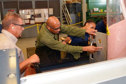 Mr. Ray Williams (L) and Hull Maintenance Technician Fireman Mionna Green (R) watch as Mr. Richard Cornwell inspects the cuts made by the new, state-of-the-art waterjet cutting system. New abrasive waterjet technology enables SERMC to cut components faster and more accurately, getting parts to the fleet more quickly. Photo by Scott Curtis