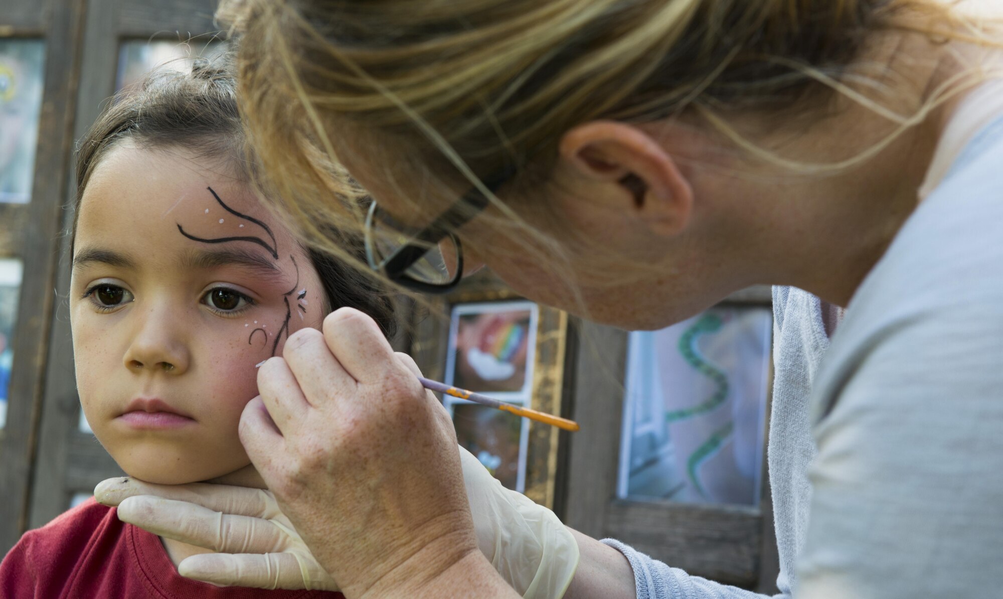 A child sits to have her face painted during the Ramstein and Vogelweh Community Center’s Olympic Family Night Aug. 22, 2016 at Ramstein Air Base, Germany. Along with face painting, children were able to compete in six events to receive a medal. (U.S. Air Force photo/Senior Airman Tryphena Mayhugh)