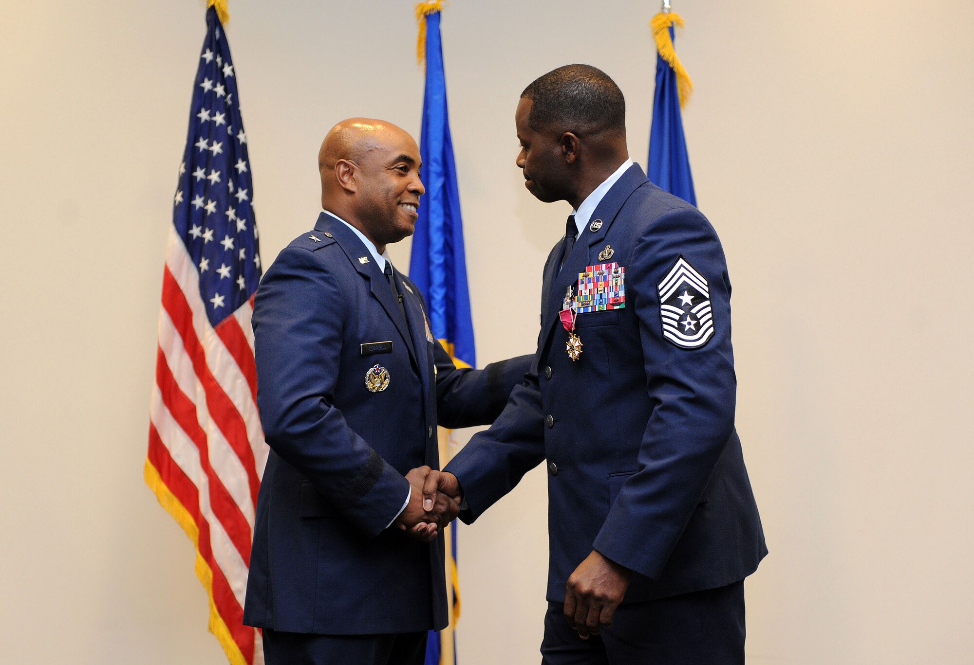Brig. Gen. Trent Edwards, Headquarters Air Force Space Command financial management and comptroller director, Peterson Air Force Base, Colo., shakes the hand of Chief Master Sgt. Harry Hutchinson, 81st Training Wing command chief, following the presentation of the Legion of Merit during his retirement ceremony at the Roberts Consolidated Aircraft Maintenance Facility Aug. 19, 2016, on Keesler AFB, Miss. Hutchinson retired with more than 29 years of military service and served multiple assignments in Washington, Korea, Maryland, Japan, Nevada, South Dakota and Africa. He also worked as the superintendent of the U.S. Army’s RED HORSE sites in Iraq and Afghanistan and the Air Force’s 732nd Expeditionary Prime BEEF squadron. (U.S. Air Force photo by Kemberly Groue/Released)