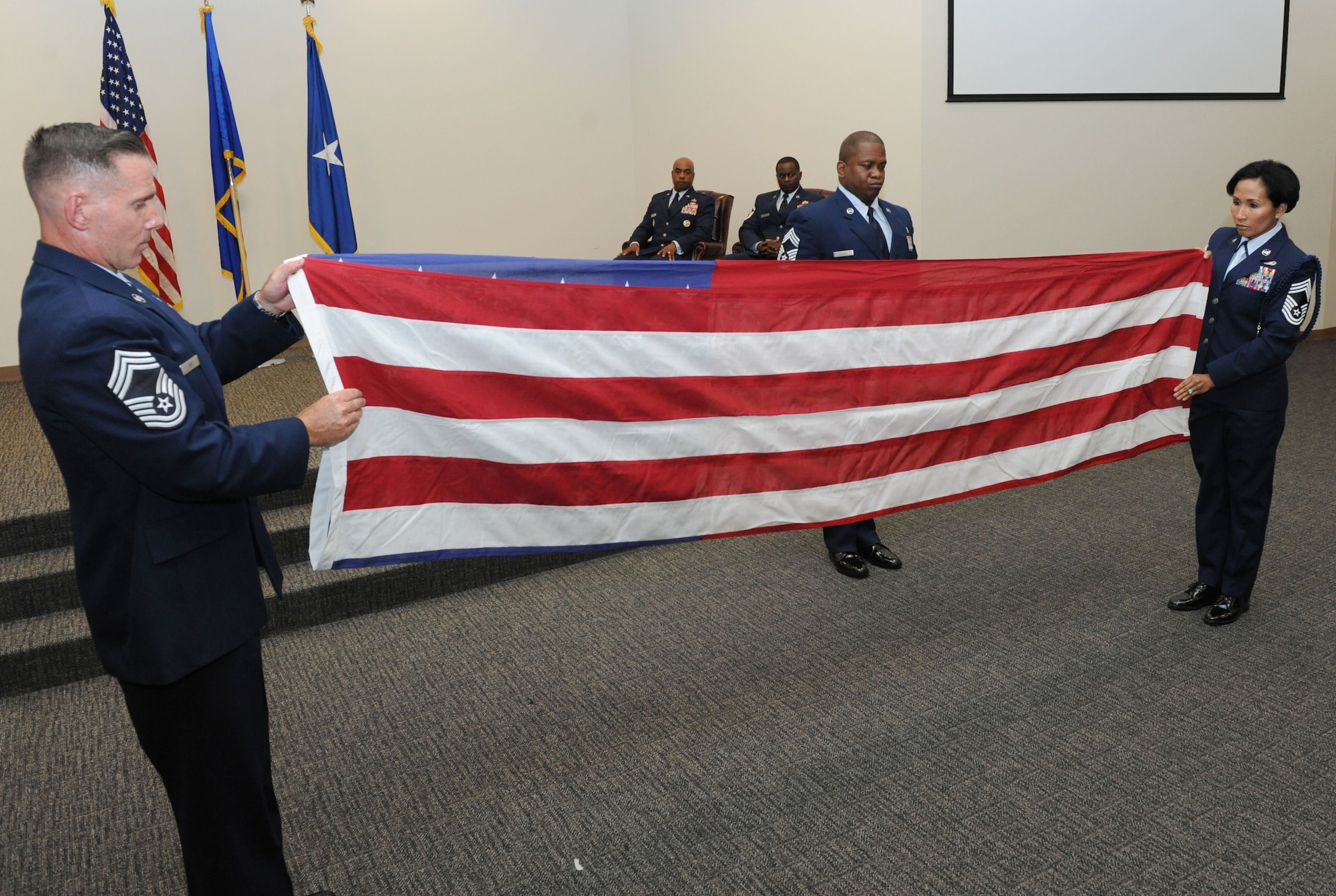 Chief Master Sgt. Karl Day, 81st Medical Group superintendent, leads a flag folding ceremony during Chief Master Sgt. Harry Hutchinson, 81st Training Wing command chief’s,  retirement ceremony at the Roberts Consolidated Aircraft Maintenance Facility Aug. 19, 2016, on Keesler Air Force Base, Miss. Hutchinson retired with more than 29 years of military service and served multiple assignments in Washington, Korea, Maryland, Japan, Nevada, South Dakota and Africa. He also worked as the superintendent of the U.S. Army’s  RED HORSE sites in Iraq and Afghanistan and the Air Force’s 732nd Expeditionary Prime BEEF squadron. (U.S. Air Force photo by Kemberly Groue/Released)