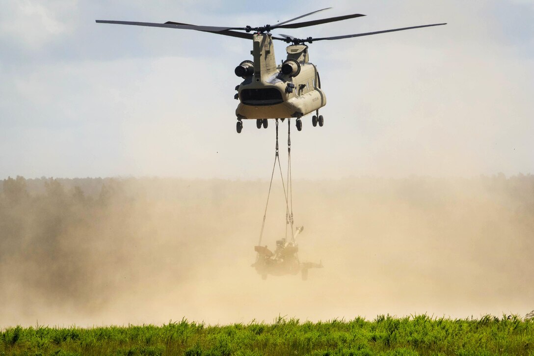 A CH-47 Chinook helicopter lifts off as it slingloads an M777A2 howitzer during a gun raid and live-fire exercise at Fort Bragg, N.C., Aug 12, 2016. Army photo by Capt. Adan Cazarez