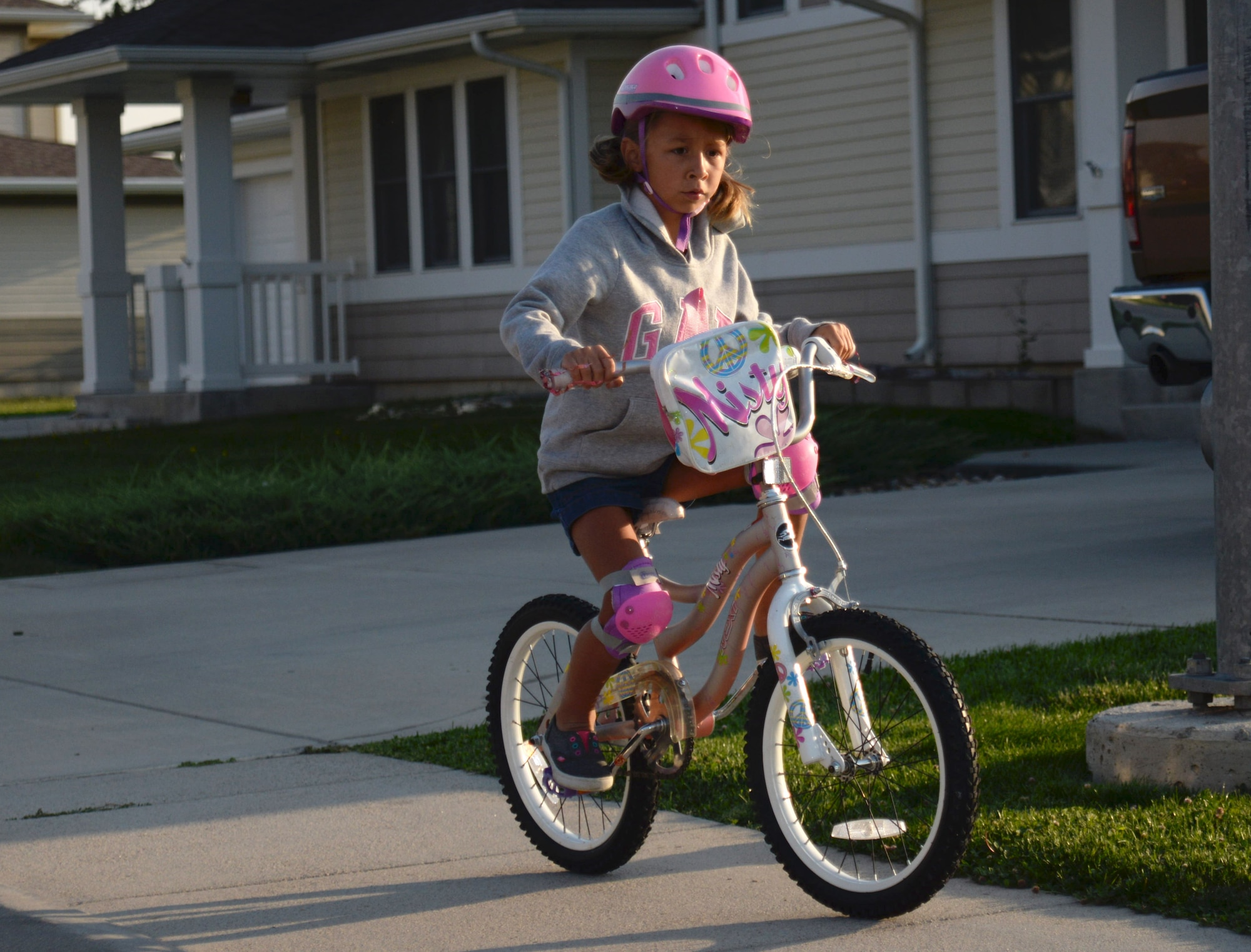 Adryanna Holguin, daughter of Airman 1st Class Teresa Stine, a broadcast journalist apprentice assigned to the 28th Bomb Wing Public Affairs office, rides her bicycle through base housing at Ellsworth Air Force Base, S.D., Aug. 23, 2016. While riding bicycles on base, both children and adults must wear proper safety equipment, including helmets and knee pads. (U.S. Air Force photo by Airman 1st Class Denise M. Jenson)