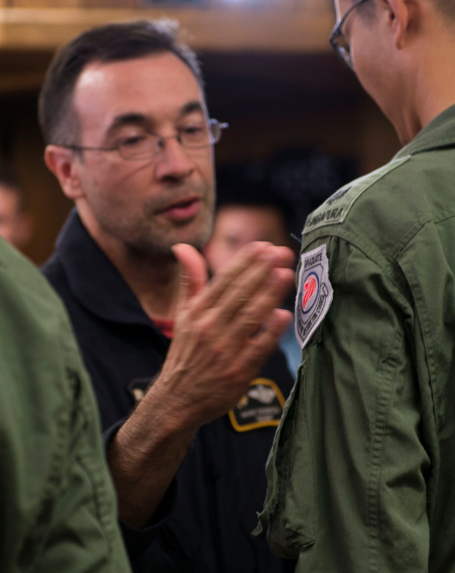 Mark Thompson, 428th Fighter Squadron F-15SG instructor pilot, patches Republic of Singapore Air Force Maj. Wang Kee Yong, 428th Fighter Squadron F-15SG pilot, during a patching ceremony July 22, 2016 at Mountain Home Air Force Base, Idaho. Normally limited to "patches," aircrew who have already earned their instructor patches, the ceremony marks the transition from student to teacher. (U.S. Air Force photo by Senior Airman Lauren-Taylor Levin/Released)
