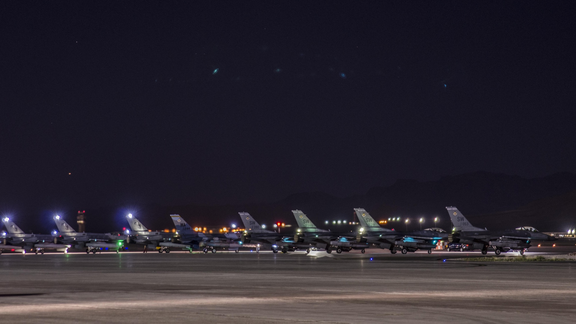 An F-16C Fighting Falcon from the 64th Aggressor Squadron, Nellis Air Force Base, Nev., awaits permission to take off on a taxiway between three F‐16Cs from the 5th Squadron, Rafiqui AFB, Pakistan, and four U.S. F-16CMs from the 55th Fighter Squadron, Shaw AFB, S.C., during a night sortie at Nellis AFB, Aug. 17, 2016. Red Flag 16-4 took place Aug. 15 - Aug. 26 and involved players from every branch of service as well as multiple nations. (U. S. Air Force photo by Tech. Sgt. Frank Miller)