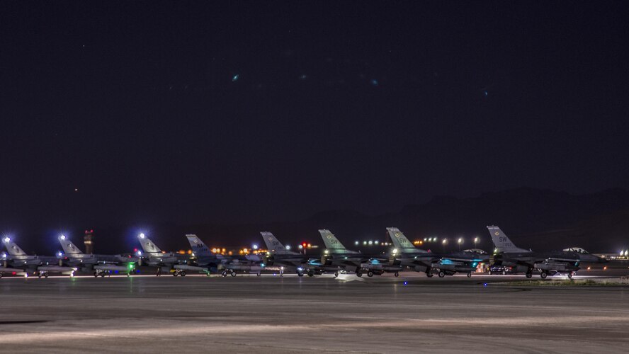 An F-16C Fighting Falcon from the 64th Aggressor Squadron, Nellis Air Force Base, Nev., awaits permission to take off on a taxiway between three F‐16Cs from the 5th Squadron, Rafiqui AFB, Pakistan, and four U.S. F-16CMs from the 55th Fighter Squadron, Shaw AFB, S.C., during a night sortie at Nellis AFB, Aug. 17, 2016. Red Flag 16-4 took place Aug. 15 - Aug. 26 and involved players from every branch of service as well as multiple nations. (U. S. Air Force photo by Tech. Sgt. Frank Miller)