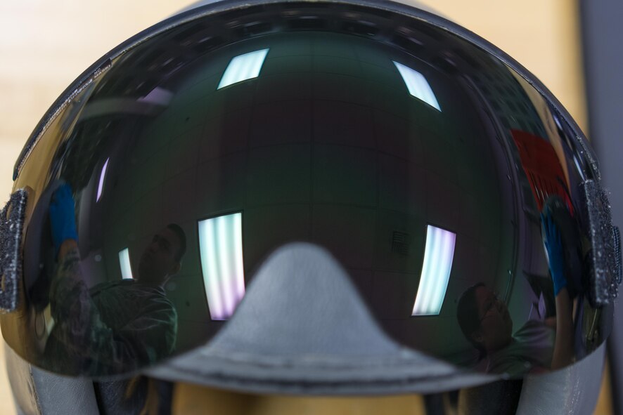 The reflection off of a flight helmet visor shows 374th Operations Support Squadron aircrew flight equipment members inspecting helmets during Red Flag-Alaska at Joint Base Elmendorf-Richardson, Alaska, Aug. 20, 2016. Aircrew Flight Equipment specialists with the 374th Operations Support Squadron make sure aircrew have the supplies necessary for their missions. (U.S. Air Force photo by Staff Sgt. Michael Smith/Released)