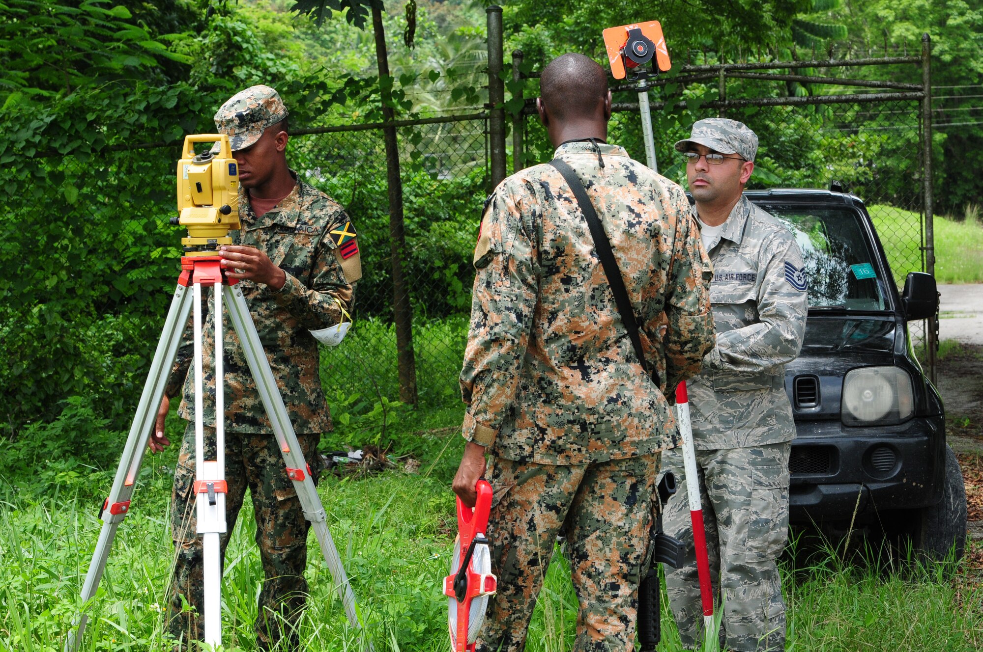 Tech. Sgt. Gursimran Shergill, 113th Civil Engineer Squadron engineer, works with members from the Jamaica Defence Force 1 Engineer Regiment in Montego Bay, Jamaica Aug. 4. The team used survey equipment to map the area around a building the JDF plan to turn into a training site for military police. (U.S. Air National Guard photo by Senior Airman Erica Rodriguez)