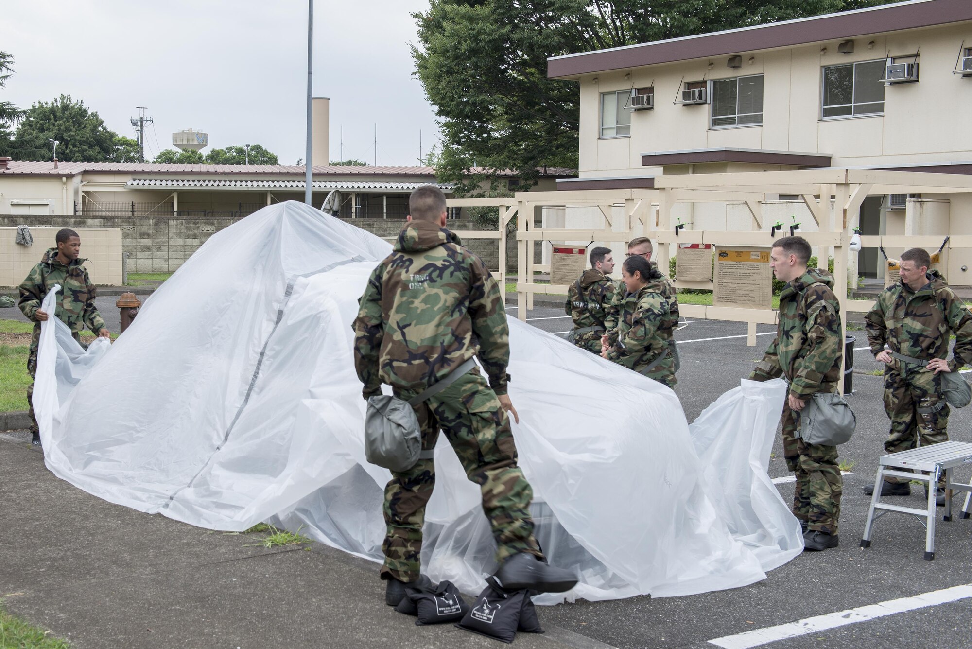 Airmen practice asset protection by covering a vehicle with plastic sheets during a Chemical, Biological, Radiological, Nuclear and Explosives defense class at the Camp Warlord training ground at Yokota Air Base, Japan, Aug. 10, 2016. Camp Warlord provides Airmen the opportunity to practice asset protection and recovery in a hands-on environment. (U.S. Air Force photo by Senior Airman David C. Danford/Released)