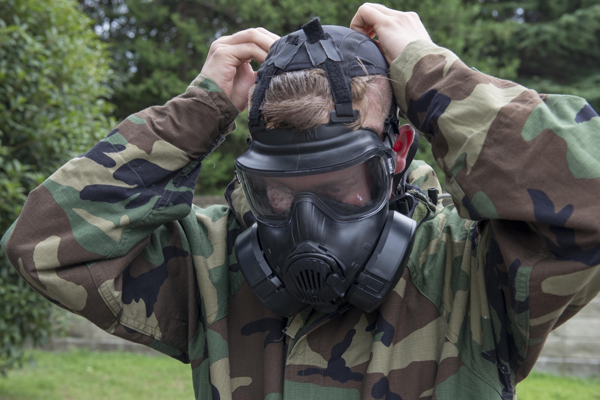 Tech. Sgt. Ryan Karr, 374th Civil Engineer Squadron Airmen dormitory leader, dons a chemical protective mask during a Chemical, Biological, Radiological, Nuclear and Explosives defense class at the Camp Warlord training ground at Yokota Air Base, Japan, Aug. 10, 2016. Airmen are trained to don their protective gear quickly in case of real-world emergencies, mitigating their possible exposure to airborne hazards. (U.S. Air Force photo by Senior Airman David C. Danford/Released)