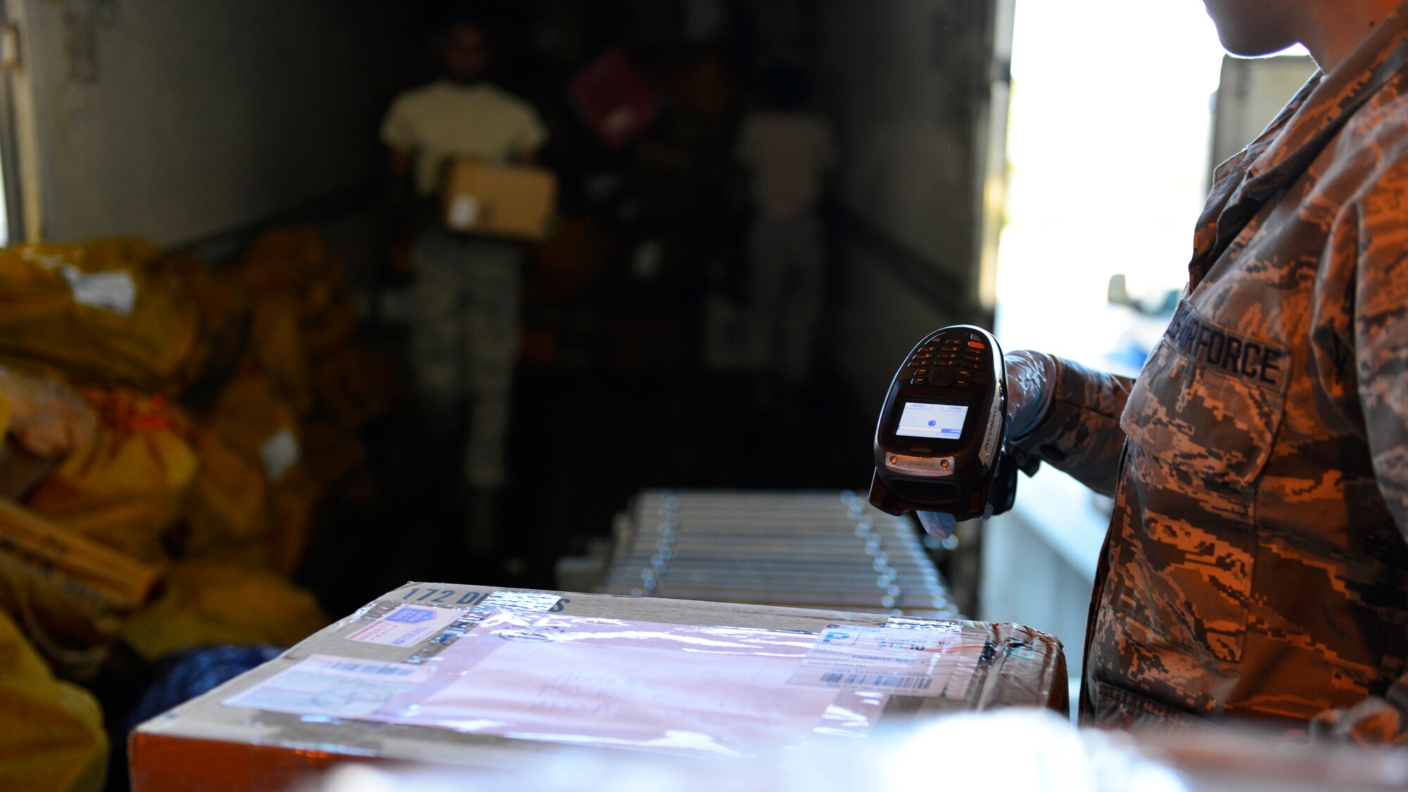 Airman 1st Class Marleny Barboza, 31st Communication Squadron postal clerk, scans a package while Airmen unload a delivery truck, Aug. 22, 2016, at Aviano Air Base, Italy. With less delivery times, Team Aviano can expect delays in receiving mail and packages through September. (U.S. Air Force photo by Airman 1st Class Cary Smith/Released)