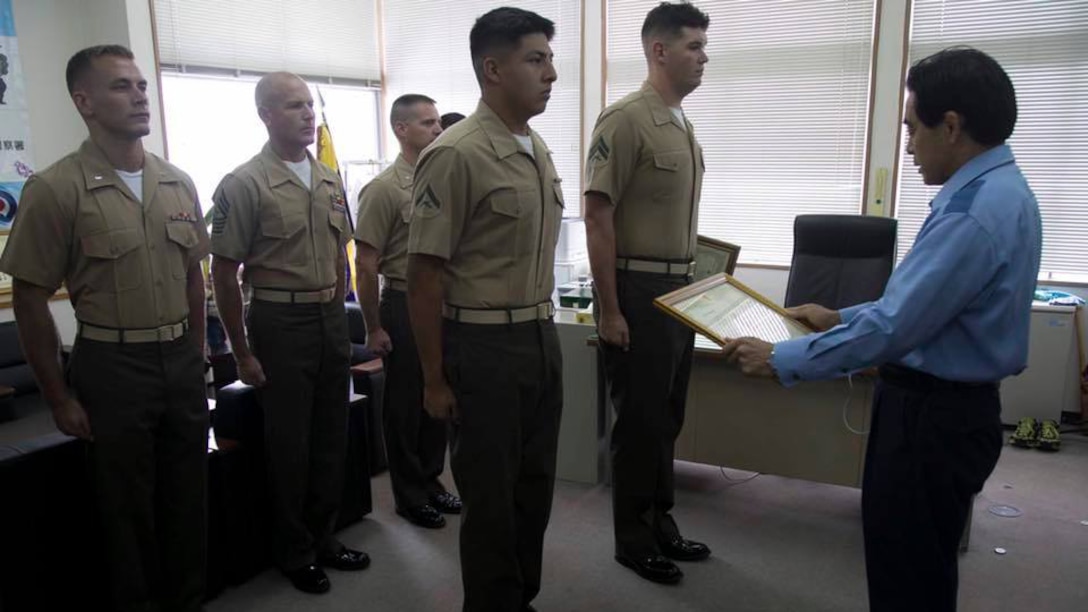 Lance Cpl. Luis Rosas, left, and Cpl. Ian Burnham, right, are presented a letter of appreciation by Eikatsu Sakihara, the Chief of the Urasoe City Police Department at the Urasoe City Police Department, Okinawa, Japan, Aug. 23, 2016. Rosas and Burnham were awarded for their efforts in assisting an Okinawa resident from a burning vehicle, and eliminating hazards at the scene of a car crash on April 16. Rosas is a Wilmington, Calif. native, and an engineer equipment mechanic with Combat Logistics Regiment-35, 3rd Maintenance Bn., 3rd Marine Logistics Group, III Marine Expeditionary Force. Burnham is a Spokane, Washington native, and electrical engineer equipment systems technician with CLR-35, 3rd Maintenance Bn., 3rd MLG, III MEF.

