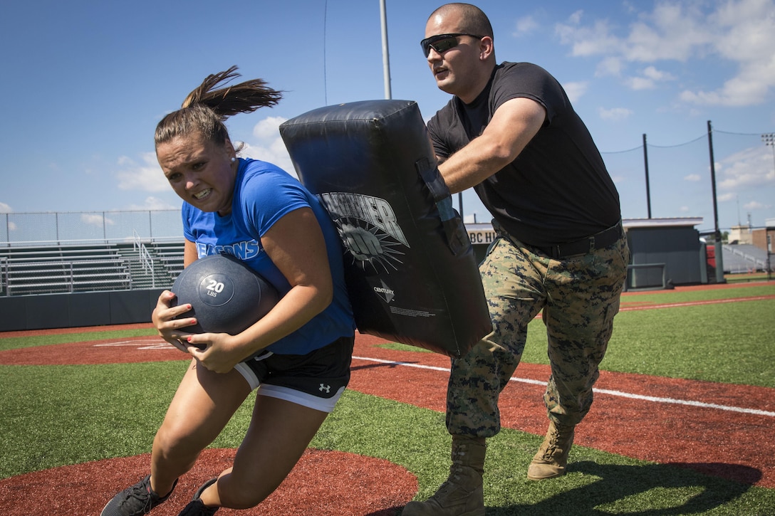 U.S. Marine Corps Sgt. Phillip Voss, a canvassing recruiter with Recruiting Substation North Boston, blocks a University of Massachusetts - Boston women’s soccer team player from completing an obstacle during a leadership seminar at the UMass Boston fields, Aug. 19. Marine Corps leadership seminars are events wherein participants are taught about what makes good individual leaders and team cohesiveness followed by a workout regimen designed to make participants exercise those leadership principles under stress.