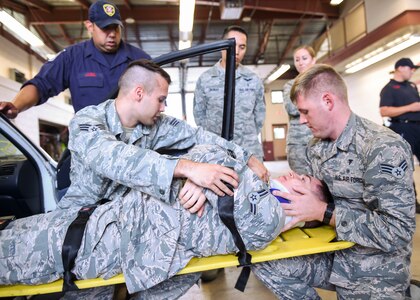 Senior Airmen Andrew Hall and Jon Paul Fitzgerald, 359th Medical Group aerospace medicine technicians, practice extracting a simulated patient from a vehicle Aug. 13, 2016 at Fire Station 11 in downtown San Antonio. (U.S. Air Force photo/Staff Sgt. Michael Ellis)