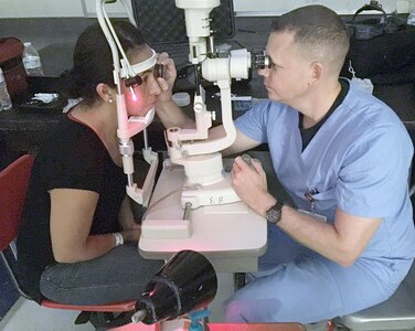 Army Maj. Brad Cunningham (right), a Brooke Army Medical Center optometry student, performs a slit lamp examination July 27 during a free optometry clinic at Juarez-Lincoln High School in Mission, Texas, during a weeklong humanitarian mission to provide vision services to people living in the Rio Grande Valley.