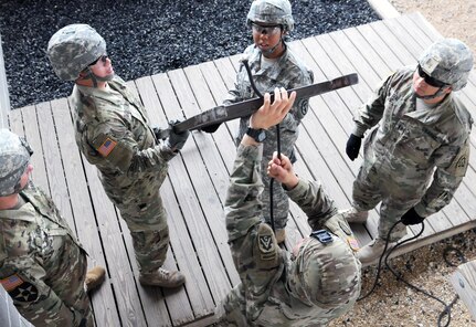 Soldiers from U.S. Army North’s Headquarters Support Company prepare a ladder to use as a bridge while maneuvering the first obstacle at the Leaders Reaction course on Camp Bullis Aug. 18. The course is designed so that each individual on a team takes on a leadership role directing, communicating, and problem-solving a specific obstacle that required both physical and mental skills to accomplish correctly.