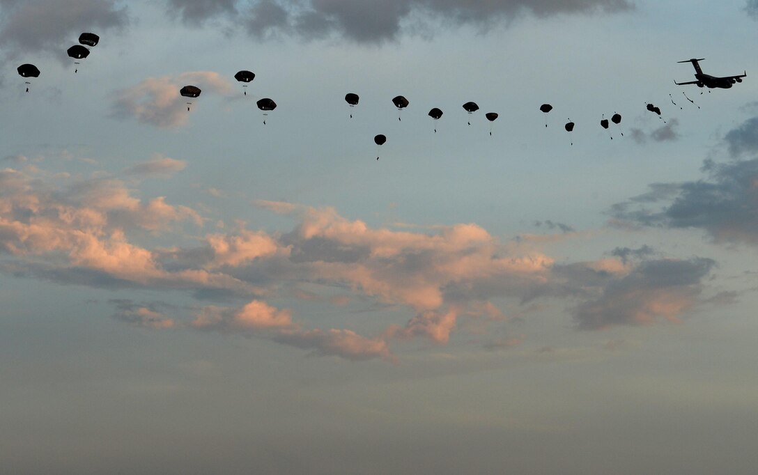 Members of the 82nd Airborne Division jump from a C-17 Globemaster III during a mass tactical parachute jump onto Sicily Drop Zone at Fort Bragg, N.C., July 12, 2016. During the battalion mass tactical week, Army and Air Force units worked together to improve interoperability for worldwide crisis, contingency and humanitarian operations. (U.S. Air Force photo/Senior Airman Ericka Engblom)