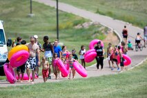 Sliders carry their tubes back up the hill following their trip down a giant slip-and-slide during Slide the City at Schriever Air Force Base, Colorado, Friday, Aug. 19, 2016. This year, the event was moved from the road next to the fitness center to a hill behind the facility to give participants a longer, steeper slide. (U.S. Air Force photo/Christopher DeWitt)