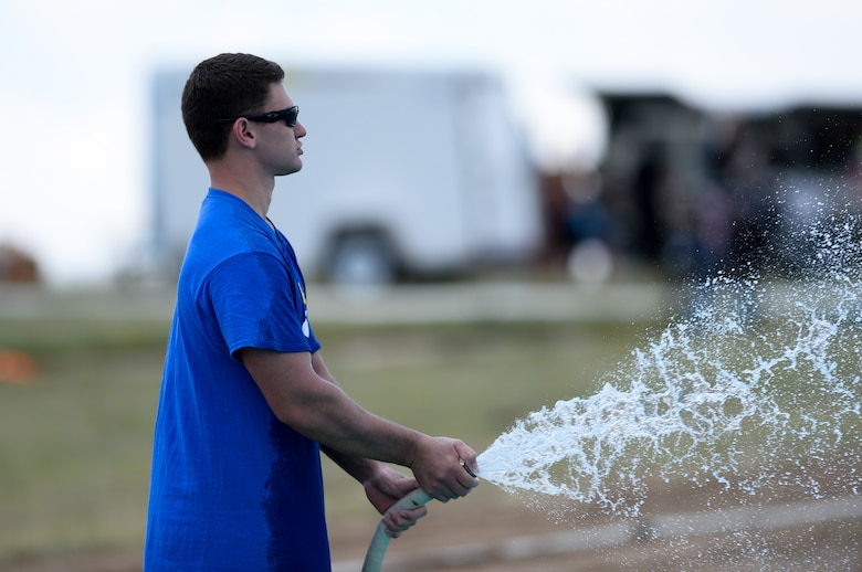 Second Lt. Ian Day, 3rd Space Operations Squadron, sprays water at sliders during Slide the City at Schriever Air Force Base, Colorado, Friday, Aug. 19, 2016. Day was one of the more than 60 volunteers during the 50th Force Support Squadron-sponsored event. (U.S. Air Force photo/Christopher DeWitt)