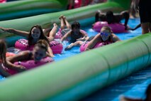 Participants slide down a giant slip-and-slide during Slide the City at Schriever Air Force Base, Colorado, Friday, Aug. 19, 2016. Slide the City returned to Schriever for a second straight year, for Team Schriever and local community members to enjoy. (U.S. Air Force photo/Christopher DeWitt)