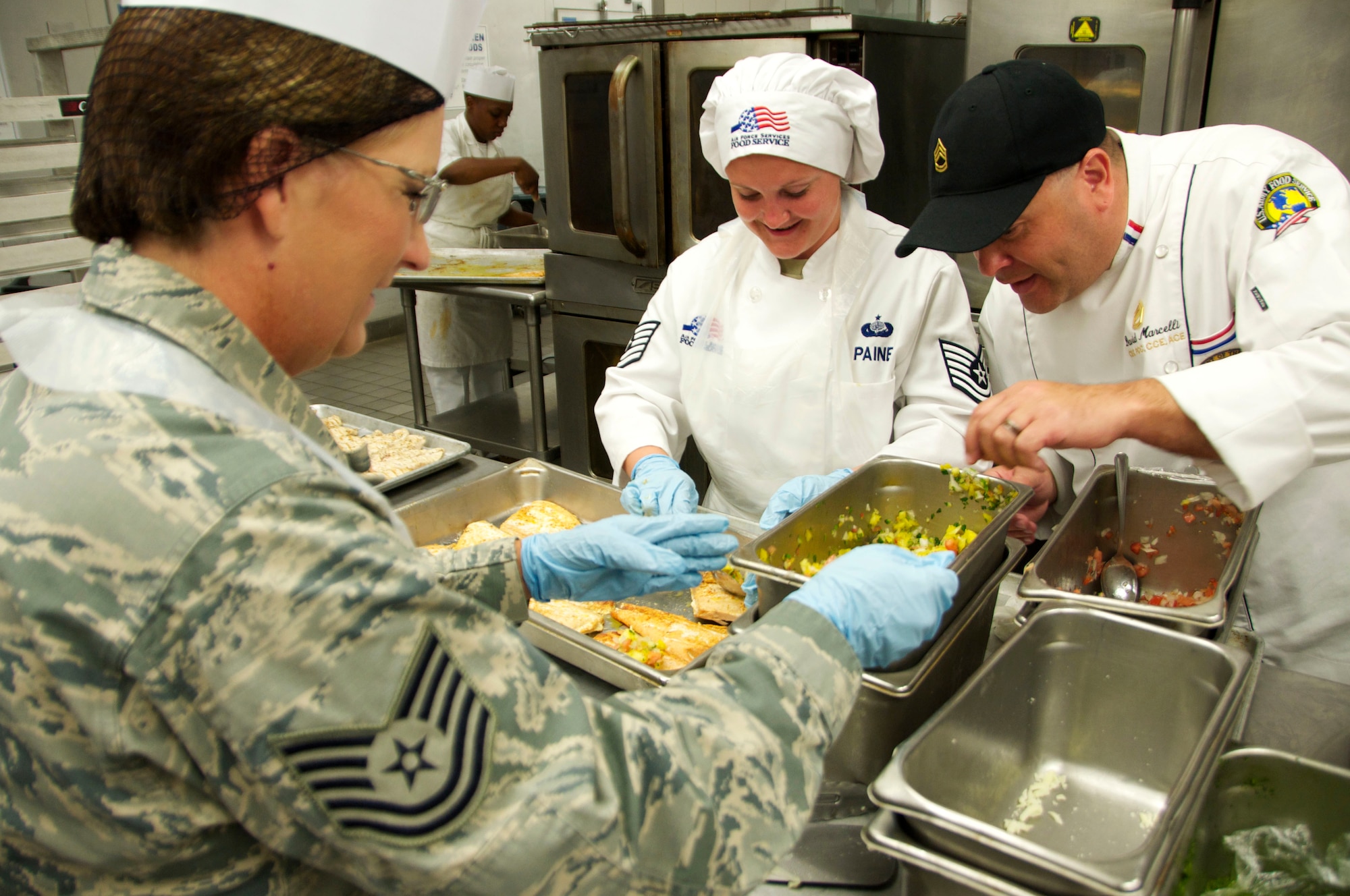 Technical Sergeants Toni Paine (center) and Stacey Macavinta (left), 419th Force Support Squadron, put the finishing touches on a meal with help from U.S. Army Sgt. First Class David Marcelli at Schofield Barracks, Hawaii. A group of 419th Fighter Wing reservists worked side by side with the seasoned chef during their two-week annual tour training, honing their skills and learning new techniques. Marcelli is head cook at Schofield Barracks and former executive chef at the Rock & Roll Hall of Fame in Cleveland, Ohio. (U.S. Air Force photo/Staff Sgt. Christina Judd)