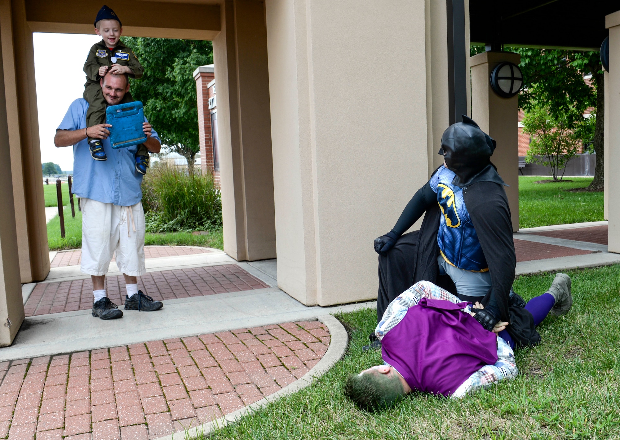 Batman, played by Tech. Sgt. Anthony Coppola, 375th Security Forces Squadron, apprehends the Joker, played by Staff Sgt. Brett Baxter, 375th SFS, with the help of Hayden Brown, 6, Aug. 17, 2016, Scott Air Force Base, Ill. Scott Airmen teamed up with Alton VFW Post 1308 to present Hayden with a badge of courage for his determination in dealing with his rare, and terminal illness, known as MLD.  (U.S. Air Force photo by Senior Airman Megan Friedl)