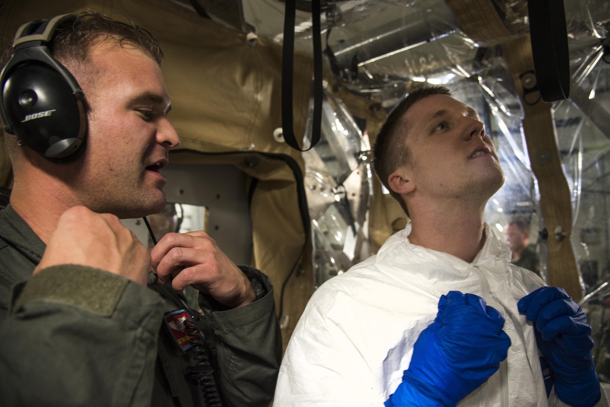 Staff Sgt. Branden Beers, 375th Aeromedical Evacuation Squadron aeromedical evacuation technician, instructs Capt. Micheal Broome 375th AES flight nurse, on how to take off his paper suit while exiting a Transportation Isolation System used for training, Aug. 18, 2016. The TIS is used to transport sick and contagious patients to more definitive care without compromising the safety of the crew. (U.S. Air Force Photo by Airman Daniel Garcia) 