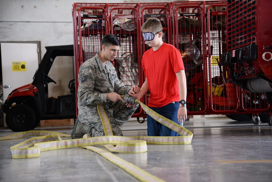Tech. Sgt. Aaron Strayhorn, 47th Civil Engineering Squadron fire inspector, teaches a junior firedog how to find his way through a cluster of tangled firehose during a week-long youth firefighting camp, on Laughlin Air Force Base, Texas, Aug. 18, 2016. The objective was to simulate escaping a fire with minimal vision while staying safe. (U.S. Air Force photo/Airman 1st Class Benjamin N. Valmoja)