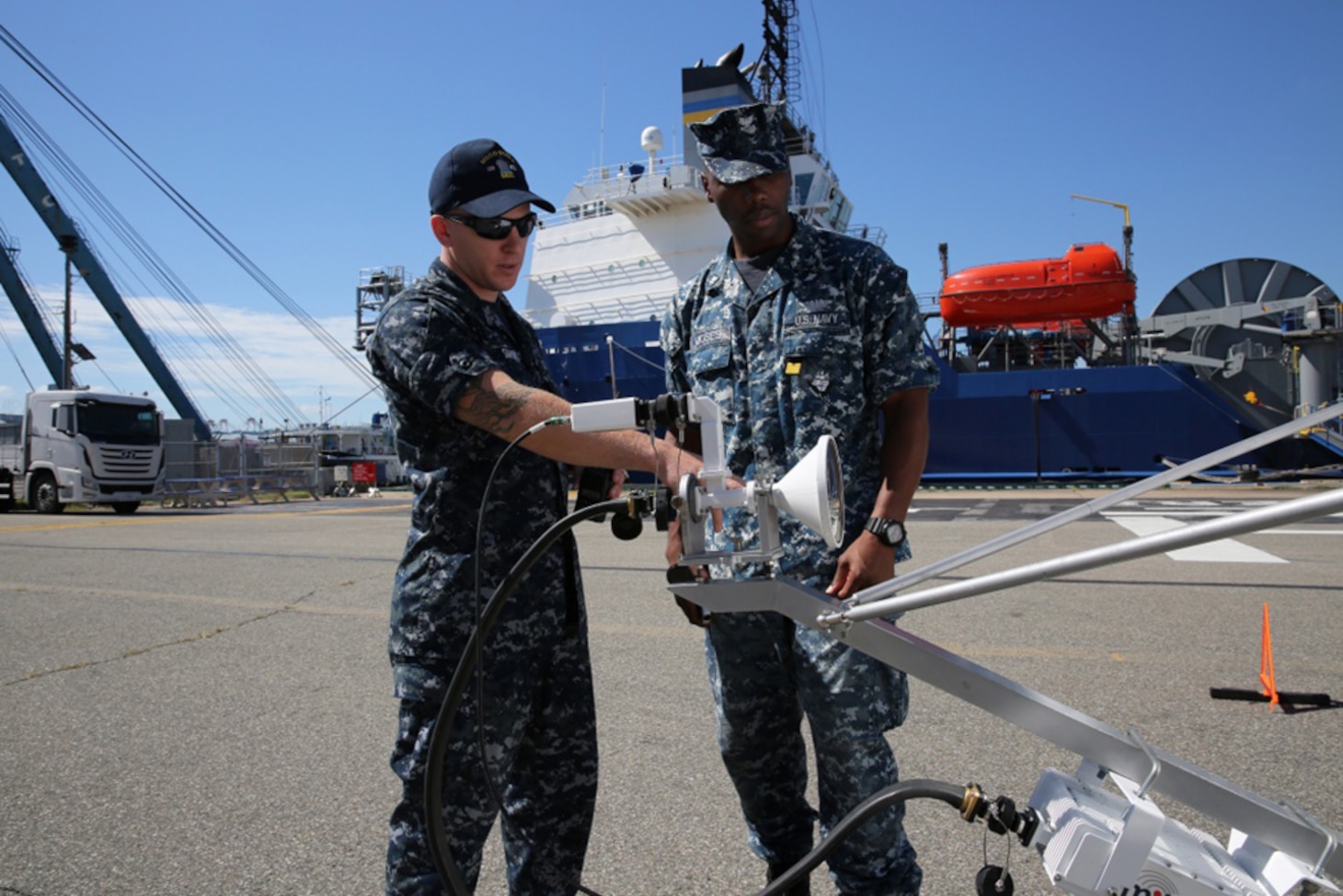 Information Systems Technician 2nd Class Dylan Simons (left) and Yeoman 2nd Class Sir Joseph Moses, both with Reserve Unit Expeditionary Port Unit 115, out of Honolulu, examine a satellite dish at Pier 8 here, Aug. 24.