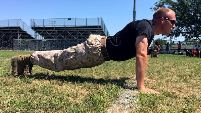 Sgt. Joseph E. Fralix, a recruiter for Recruiting Sub Station Des Moines, pushes off the ground during a push-up challenge at the Football Leadership Camp at North High School Grubb Stadium, Aug. 18. Fralix staring straight forward demonstrates bearing, one of the 14 leadership traits in the Marine Corps. (U.S. Marine Corps photo by Cpl. Jennifer Webster/Released)
