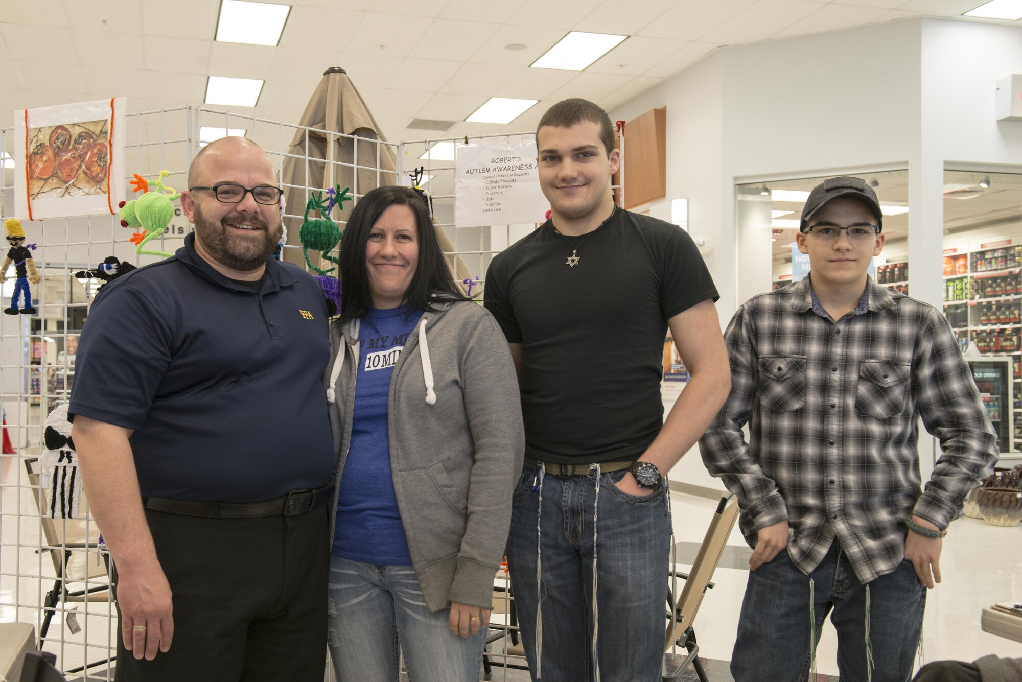 Department of the Air Force Jack Waid, the 354th Fighter Wing historian, stands with his wife, Jami and sons, Robert and Joshua in the Base Exchange atrium April 22, 2016, at Eielson Air Force Base, Alaska. The Waid family supports Robert, who creates and sells many pieces of artwork and raises awareness about autism. (U.S. Air Force photo by Staff Sgt. Ashley Nicole Taylor)