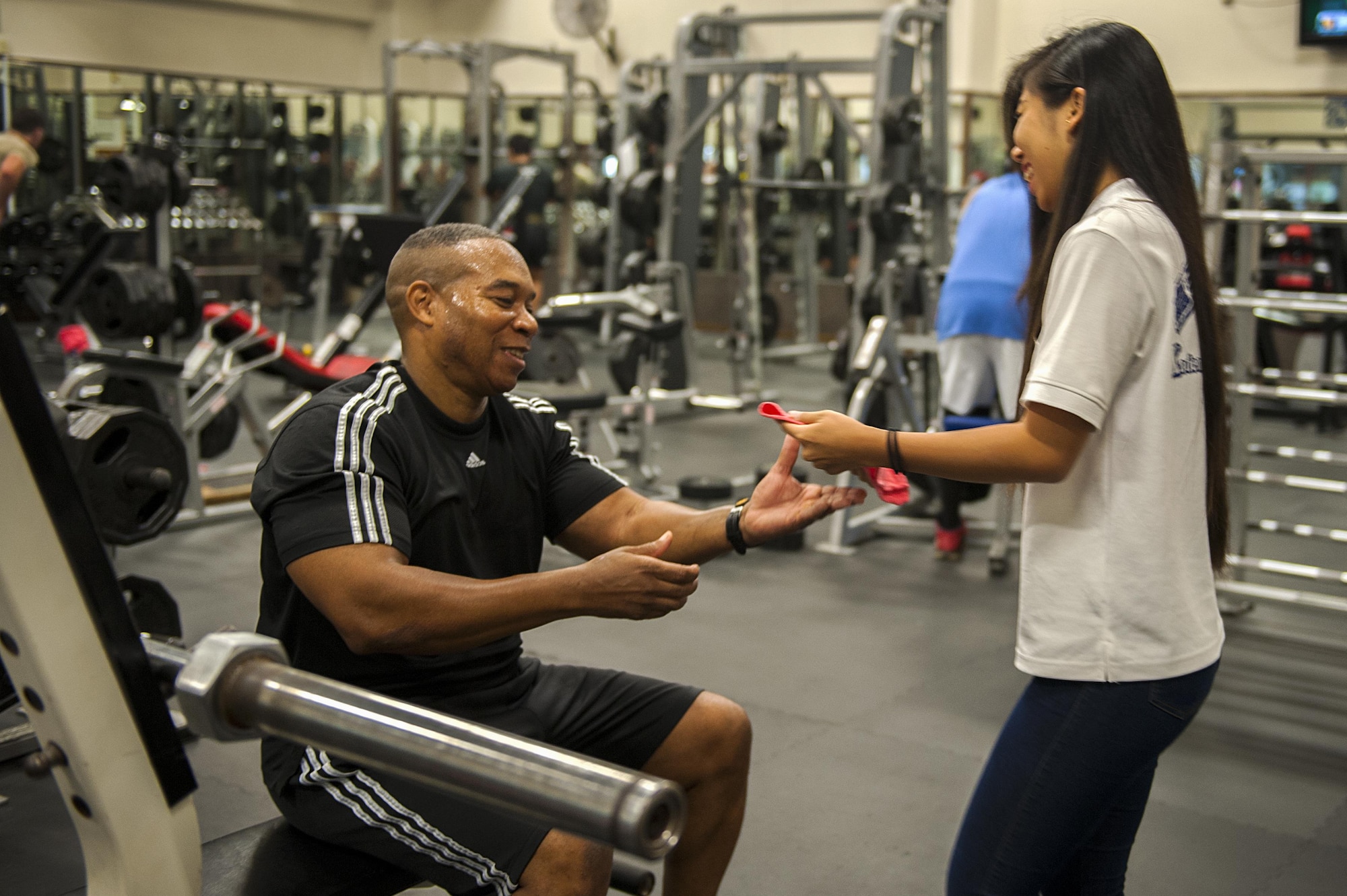 Yuka Kinjo, 18th Force Support Squadron intern, hands Larry Robertson, U.S. Navy contractor a towel during his workout Aug. 24, 2016, at Kadena Air Base, Japan. KLI students have the opportunity to intern on base for a month to refine their English speaking skills. (U.S. Air Force photo by Airman 1st Class Corey M. Pettis)