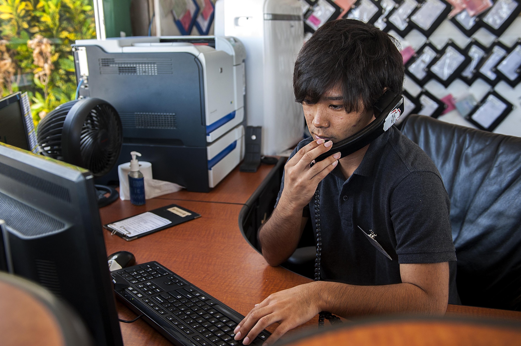 Hideya Koja, 18th Logistics Readiness Squadron intern, answers the phone Aug. 24, 2016, at Kadena Air Base, Japan. KLI interns practice their English skills and form new friendships by working with Airmen on Kadena. (U.S. Air Force photo by Airman 1st Class Corey M. Pettis)