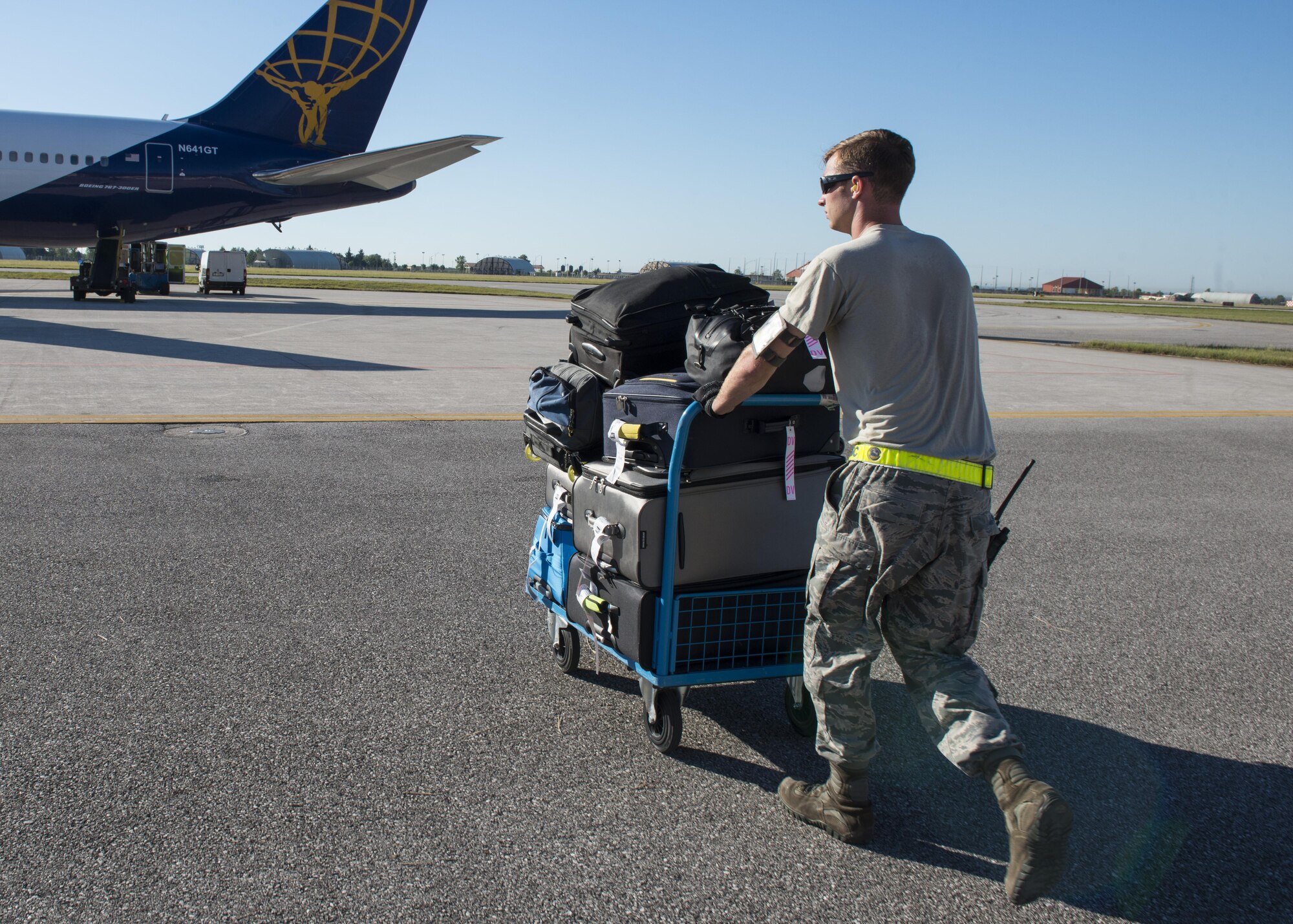 Senior Airman Thomas Harper, 724th Air Mobility Squadron passenger service agent, rolls a luggage cart toward an aircraft Aug. 24, 2016, at Aviano Air Base, Italy. The 724th AMS has facilitated the transportation of 15,841 individuals and 292 tons of cargo so far this year. (U.S. Air Force photo by Senior Airman Krystal Ardrey/Released)