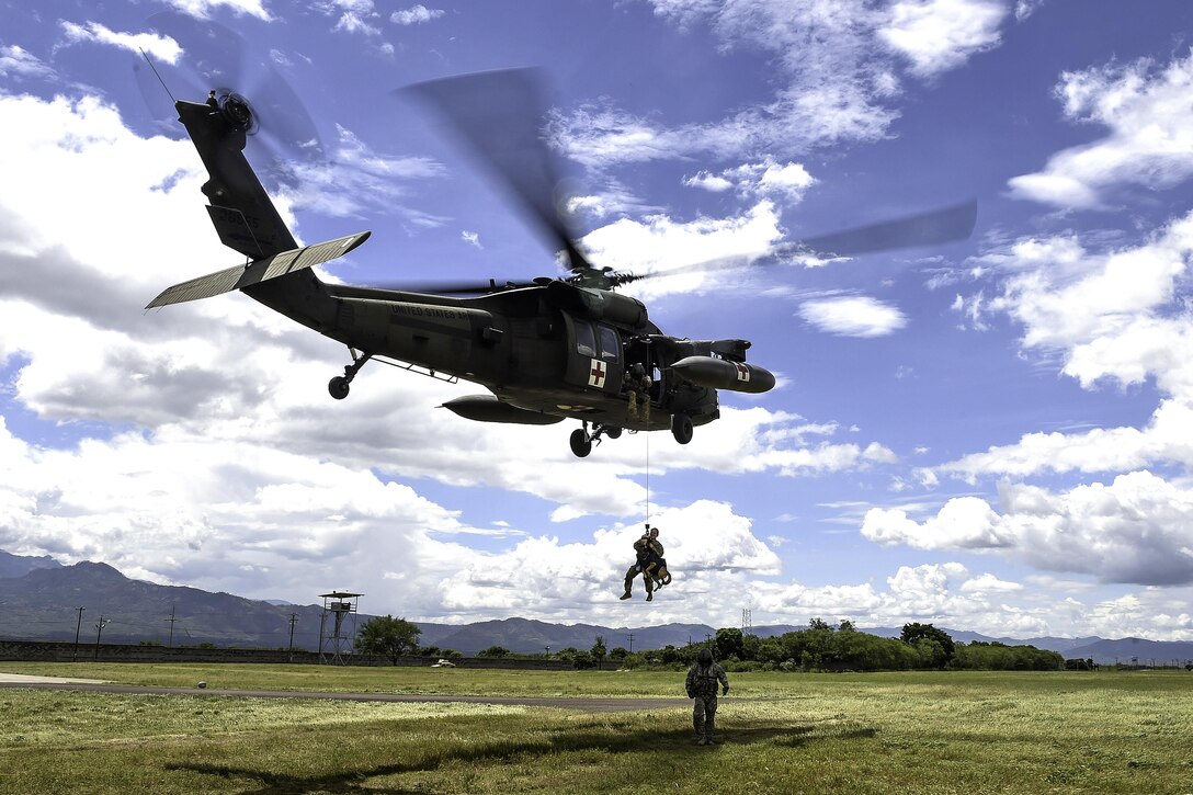 A UH-60L Black Hawk helicopter hoists Army Spc. Courtney Moreland, a military working dog handler, and her dog, Puma, during K-9 hoist evacuation training at Soto Cano Air Base, Honduras, Aug. 15, 2016. Moreland is assigned to Joint Task Force Bravo’s Joint Security Forces. Air Force photo by Staff Sgt. Siuta B. Ika
