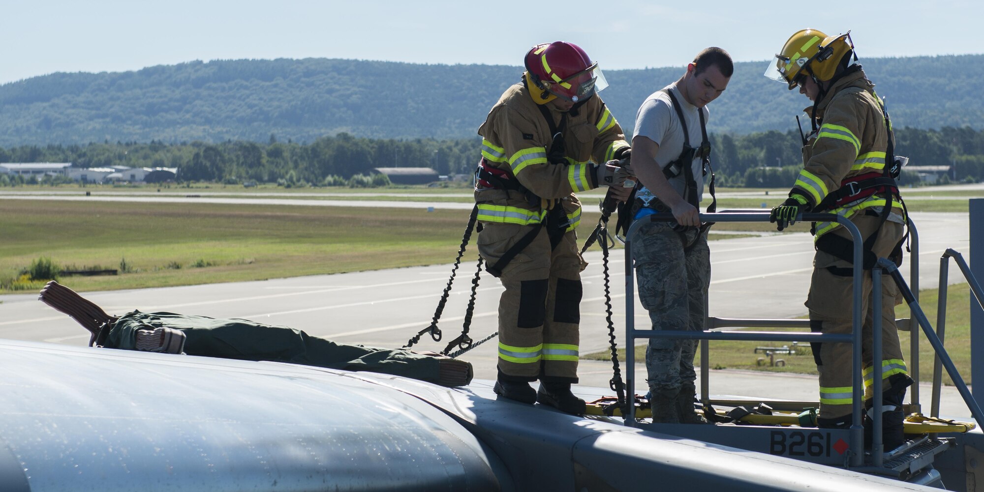 Senior Airman Gregory Pease and Lawrence Toth, 86th Civil Engineer Squadron firefighters, secure the harness of Senior Airman Justin Ivey, 721st Aircraft Maintenance Squadron fuel systems journeyman, during a training exercise Aug. 23, 2016 at Ramstein Air Base, Germany. Airmen trained atop a C-17 Globemaster III, performing rescue operations to simulate individuals needing to be removed from a plane due to an emergency. (U.S. Air Force photo/Airman 1st Class Lane T. Plummer)
