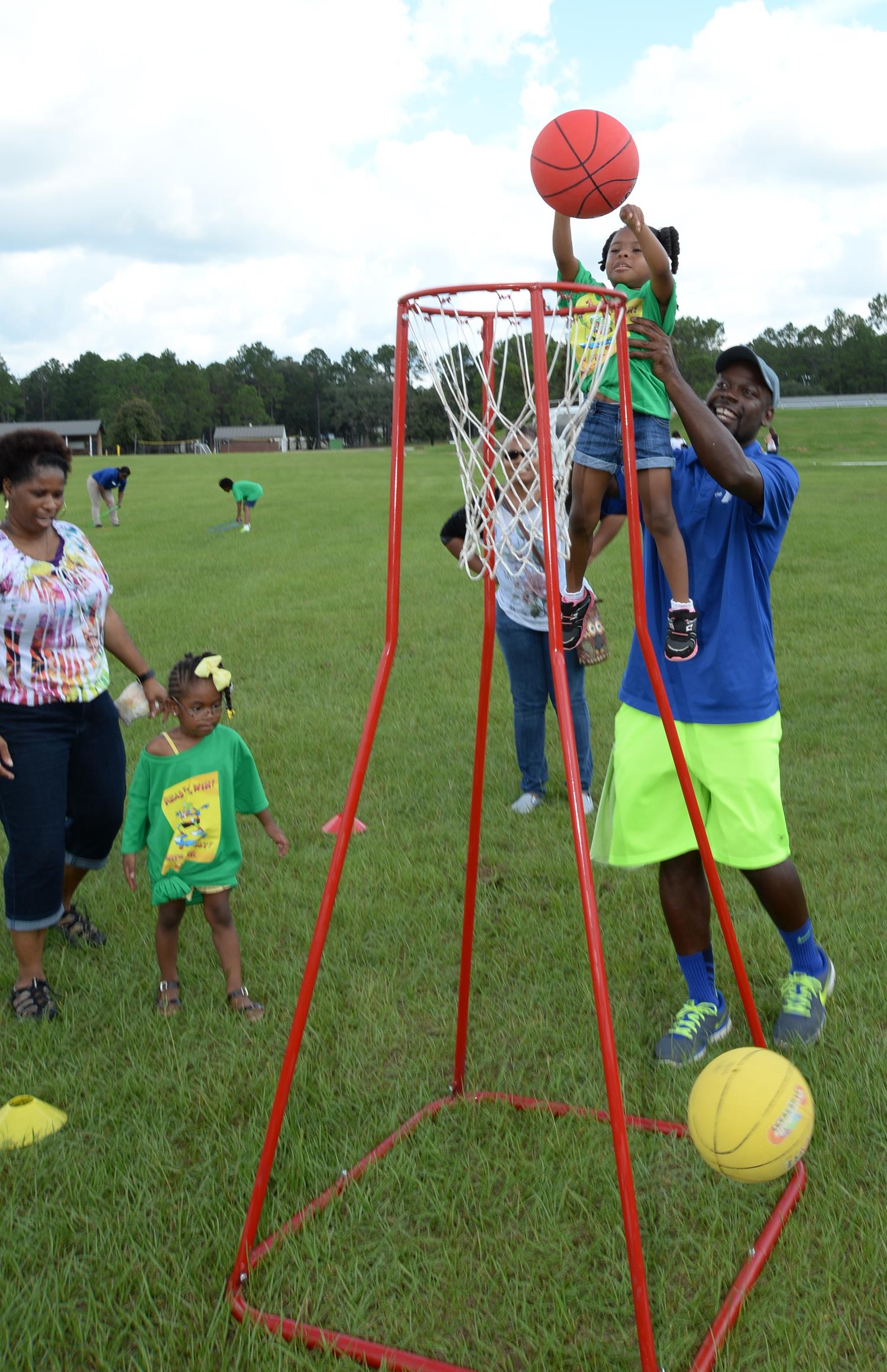 A young child receives assistance while playing basketball after Marine Corps Logistics Base Albany’s Summer Reading Awards Program at Covella Pond, Aug. 20.