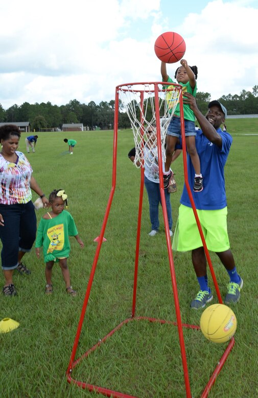 A young child receives assistance while playing basketball after Marine Corps Logistics Base Albany’s Summer Reading Awards Program at Covella Pond, Aug. 20.
